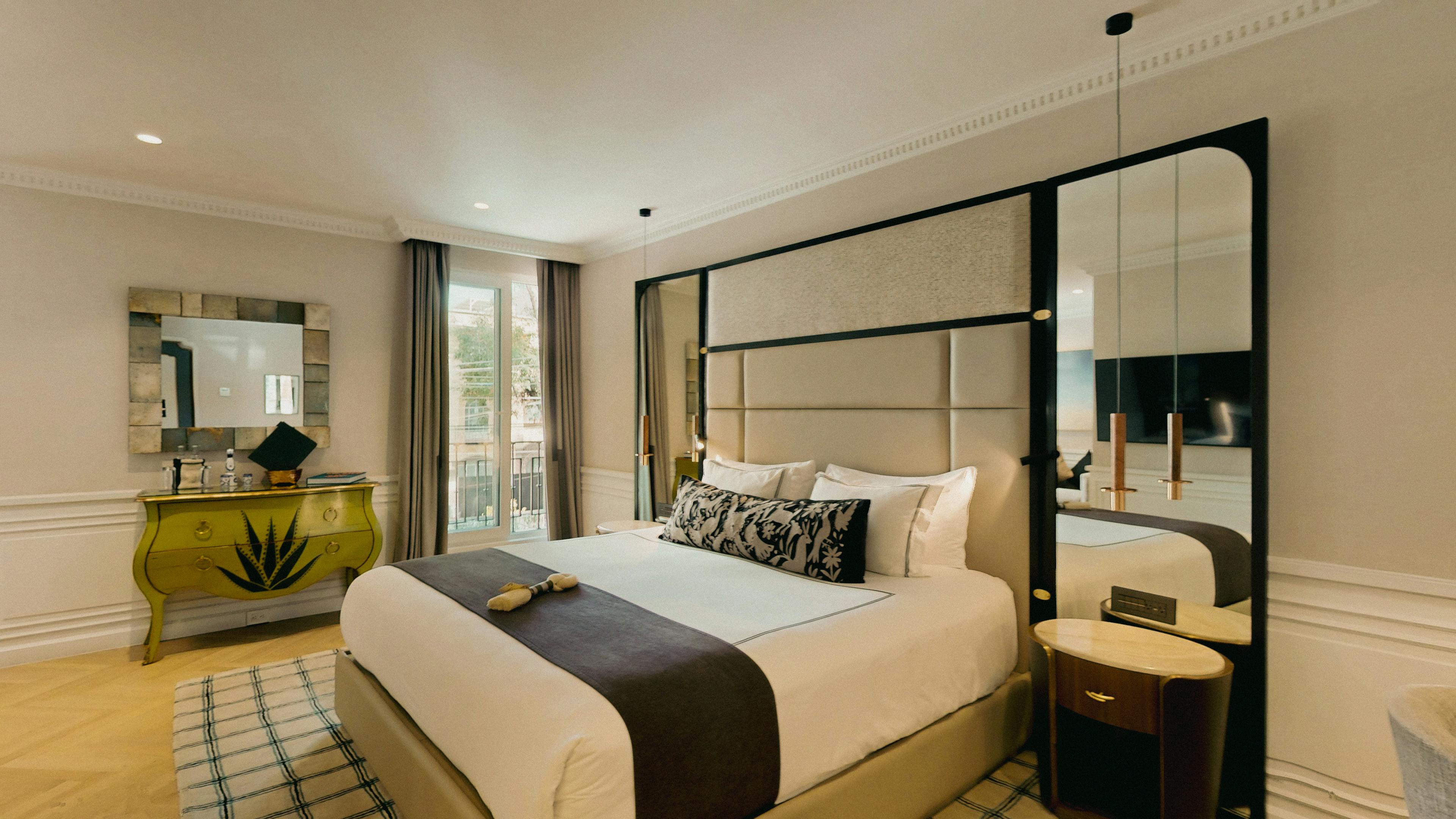 Recámara de la Grand Deluxe Room con cama King Size, consola dorada y espejo